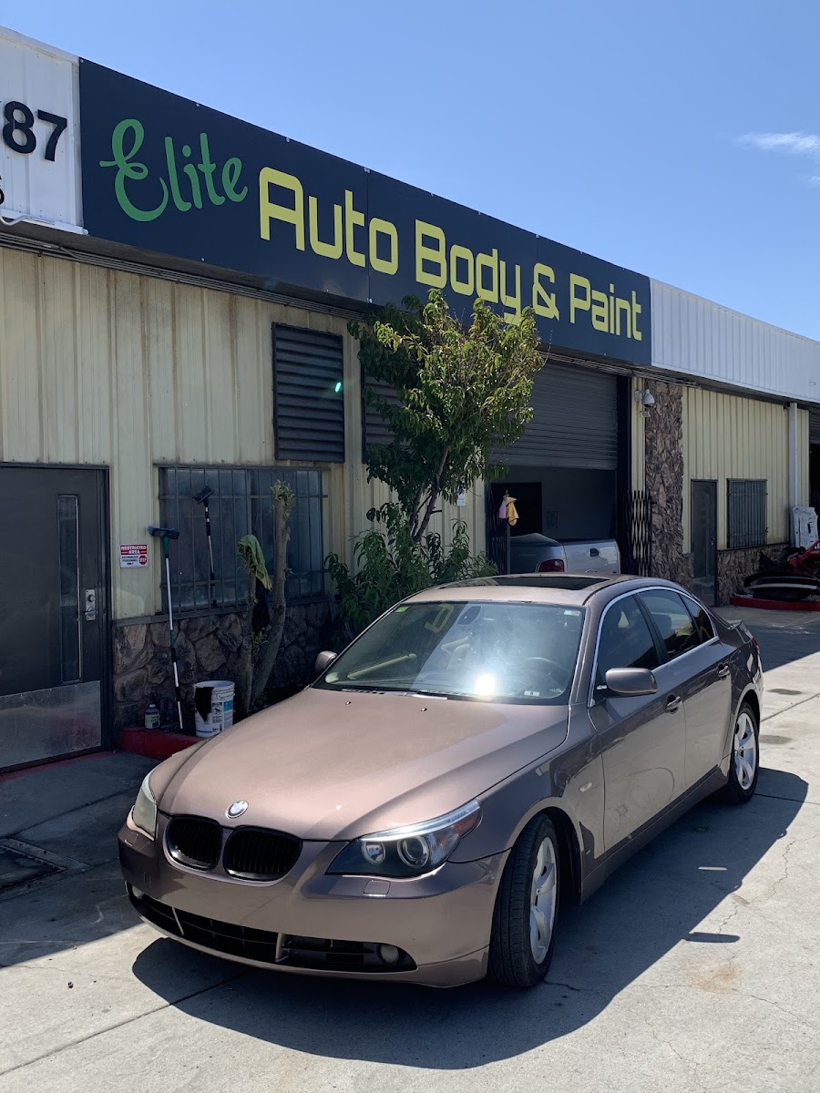 Bronze BMW parked under the Elite Auto Body & Paint sign