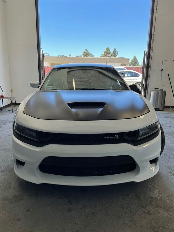 White Dodge Charger with a satin black hood in the bay